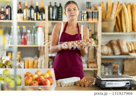 Young woman seller offering eggs in grocery store 131927966