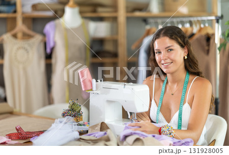 Female dressmaker working on sewing machine in workshop Female dressmaker working on sewing machine in workshop 131928005