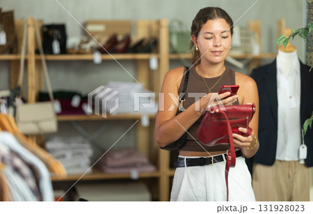 While shopping, girl scans barcode on label of handbag 131928023