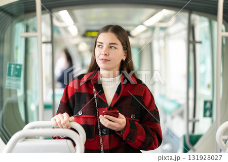 Girl with long hair standing in tram with phone Girl with long hair standing in tram with phone 131928027
