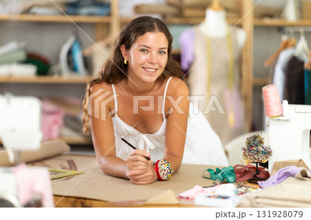 young dressmaker draws a sketch with the help of curved rulers 131928079