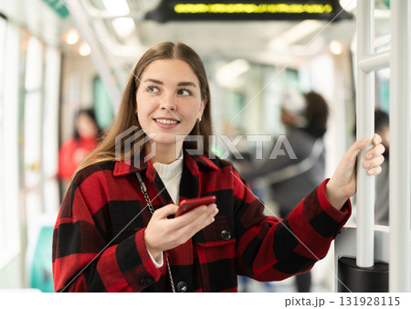 Girl is standing with phone in tram car, getting to work 131928115