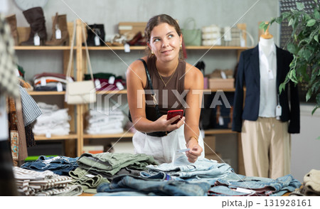 Girl scans QR code and label of denim jeans using mobile phone camera. Girl scans QR code and label of denim jeans using mobile phone camera. 131928161