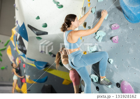 Girl climbs artificial wall bouldering, working out in gym 131928162