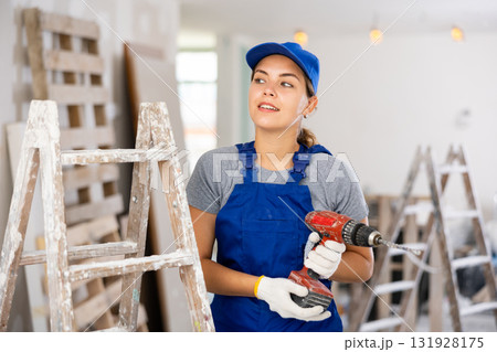 Smiling woman builder with drill, repair works in apartment 131928175