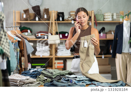 woman calls on the phone and holds her pants in her hands woman calls on the phone and holds her pants in her hands 131928184