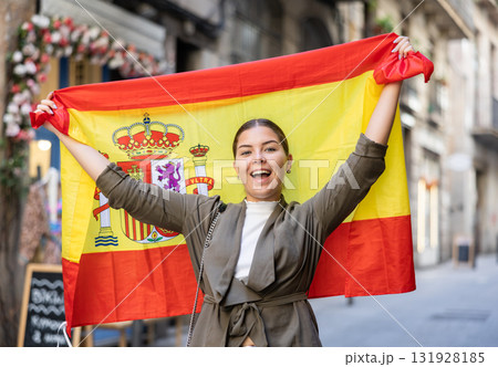 Patriotic young woman waving the flag of Spain on city street Patriotic young woman waving the flag of Spain on city street 131928185