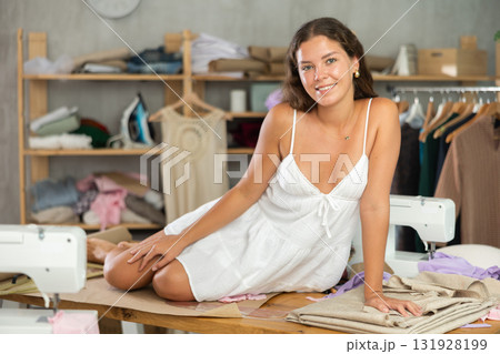 Woman playfully sitting on a table in a workshop 131928199