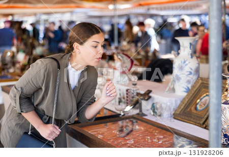 Cheerful female tourist choosing antique jewelry at flea market Cheerful female tourist choosing antique jewelry at flea market 131928206