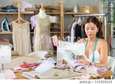 woman dressmaker sews in a workshop woman dressmaker sews in a workshop 131928228