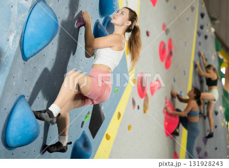 Woman exercising on wall in climbing gym during bouldering training Woman exercising on wall in climbing gym during bouldering training 131928243