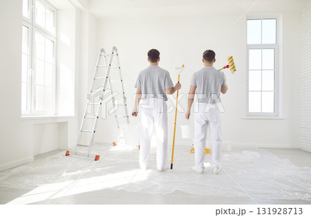 Two professional painters in light clothes going to paint a white wall. Repair concept. 131928713