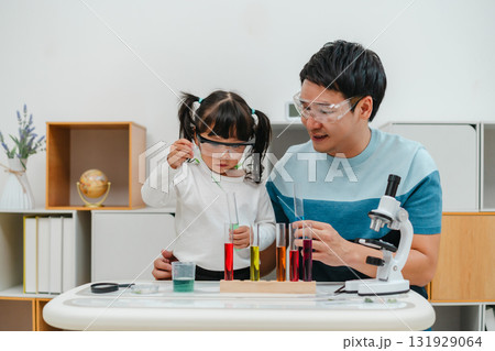 toddler girl scientist study using pipette dropping liquid with test tube and beaker. learning science with father 131929064