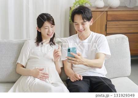 リビングでスマホを使う妊娠中の妻と夫 131929349