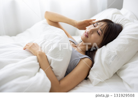 ベッドで痛そうな表情を浮かべる若い女性 ベッドで痛そうな表情を浮かべる若い女性 131929508
