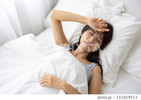 ベッドで痛そうな表情を浮かべる若い女性 ベッドで痛そうな表情を浮かべる若い女性 131929511