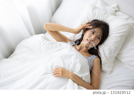 ベッドで痛そうな表情を浮かべる若い女性 ベッドで痛そうな表情を浮かべる若い女性 131929512