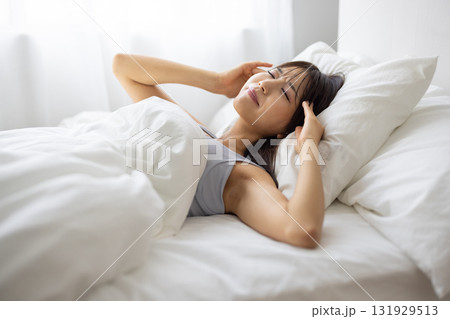 ベッドで痛そうな表情を浮かべる若い女性 ベッドで痛そうな表情を浮かべる若い女性 131929513