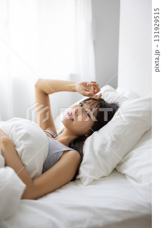 ベッドで痛そうな表情を浮かべる若い女性 131929515