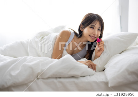 ベッドでハート型のオブジェクトを持って微笑む若い女性 131929950