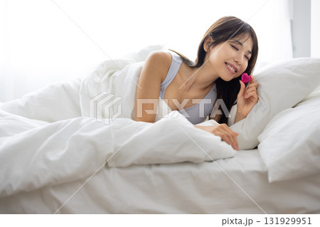 ベッドでハート型のオブジェクトを持って微笑む若い女性 131929951