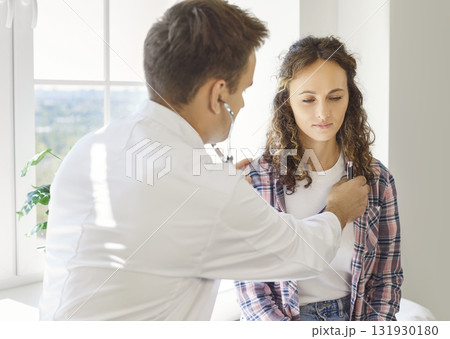 Physician using stethoscope to examine womans chest during routine checkup 131930180