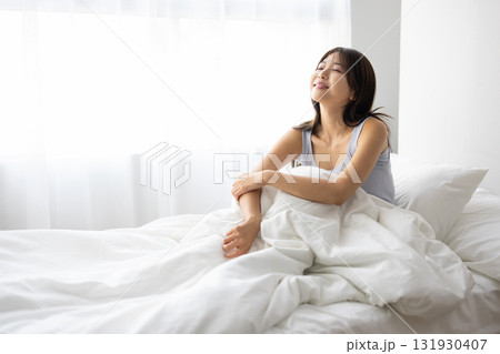 ベッドで起き上がり微笑む若い女性 ベッドで起き上がり微笑む若い女性 131930407