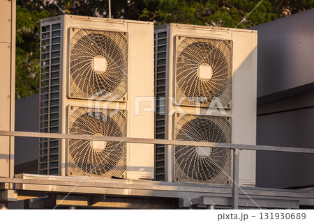 Rooftop HVAC units and ventilation systems under warm sunset light, industrial cooling and air conditioning equipment outdoors 131930689