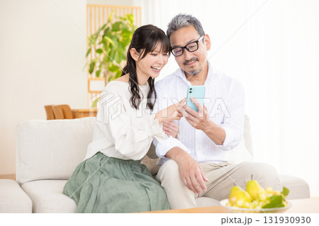 スマホを見ながら談笑するミドル夫婦 131930930