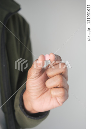 Person holding a small pink tablet in their hand indoors 131931051