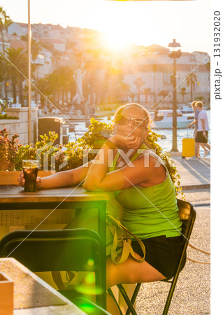 Woman relaxing at outdoor cafe enjoying sunset on Korcula Island Woman relaxing at outdoor cafe enjoying sunset on Korcula Island 131932020
