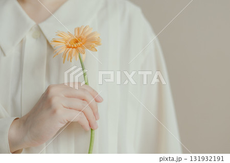 一輪のガーベラの花を持つ女性の手元 131932191