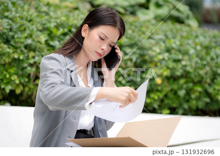 Young asian businesswoman stress reading document talking phone with upset, career crisis. Young asian businesswoman stress reading document talking phone with upset, career crisis. 131932696