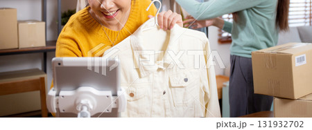 Two young asian woman live online clothing store while showing clothing with tablet and laptop. Two young asian woman live online clothing store while showing clothing with tablet and laptop. 131932702