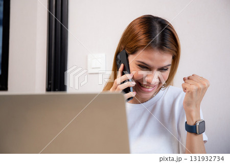 Young caucasian businesswoman talking with smartphone and working on laptop with glad. 131932734