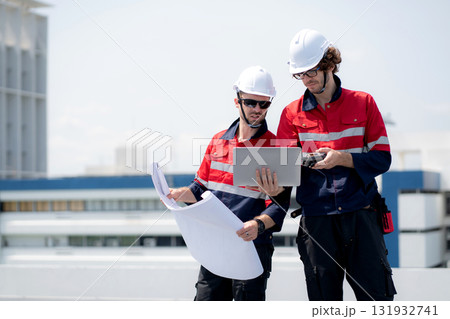 Two engineer checking solar energy system looking blueprint for planning installation solar panel. 131932741