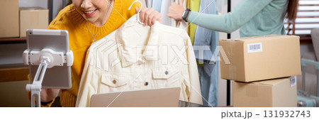 Two young asian woman live online clothing store while showing clothing with tablet and laptop. Two young asian woman live online clothing store while showing clothing with tablet and laptop. 131932743