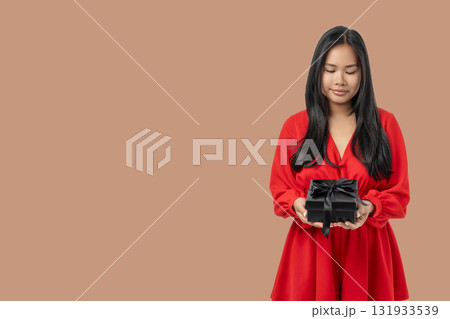 Woman in red dress smiles with gift box on Black Friday 131933539