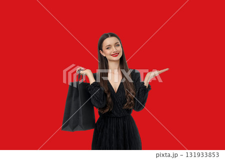Woman with long hair in black dress holding shopping bag Woman with long hair in black dress holding shopping bag 131933853