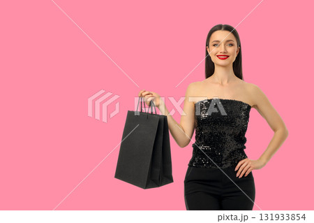 Woman poses confidently holding a black shopping bag Woman poses confidently holding a black shopping bag 131933854