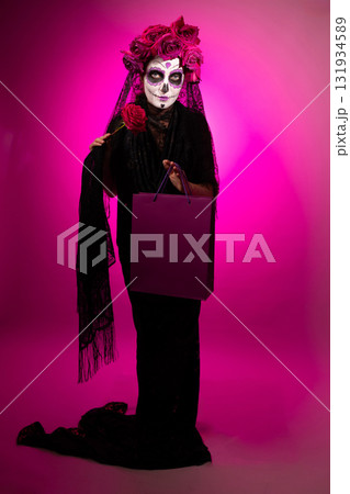 Woman Dressed as Calavera for Dia De Muertos Holding Rose and Shopping Bag 131934589