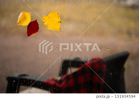 Autumn Rain Streaks Down Window With Leaves and a Chair in the Background Autumn Rain Streaks Down Window With Leaves and a Chair in the Background 131934594