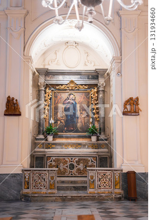 An ornate altar in an Amalfi church features a Virgin Mary painting, gold detailing, marble columns, potted plants, and patterned marble flooring. An ornate altar in an Amalfi church features a Virgin Mary painting, gold detailing, marble columns, potted plants, and patterned marble flooring. 131934660