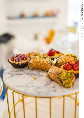 Close up of Italian pastries, including pistachio cannoli and strawberry tartlets, arranged on a marble patterned platter in Amalfi, Italy. Close up of Italian pastries, including pistachio cannoli and strawberry tartlets, arranged on a marble patterned platter in Amalfi, Italy. 131934833
