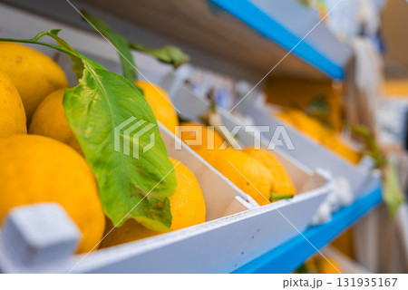 Vibrant yellow lemons with green leaves displayed in white wooden crates with blue accents, suggesting a market setting in Amalfi, Italy. Vibrant yellow lemons with green leaves displayed in white wooden crates with blue accents, suggesting a market setting in Amalfi, Italy. 131935167
