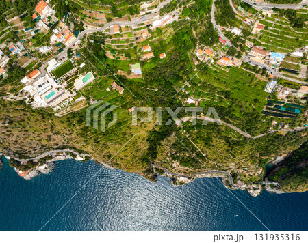 Aerial image of the Amalfi Coast in Italy, featuring terraced hillsides, luxury villas, winding roads, and cliffs descending to the Tyrrhenian Sea. Aerial image of the Amalfi Coast in Italy, featuring terraced hillsides, luxury villas, winding roads, and cliffs descending to the Tyrrhenian Sea. 131935316