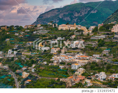 Aerial view of Ravello, Italy, featuring terraced hills, Mediterranean style buildings, villas, churches, gardens, olive groves, and rugged mountains. Aerial view of Ravello, Italy, featuring terraced hills, Mediterranean style buildings, villas, churches, gardens, olive groves, and rugged mountains. 131935471