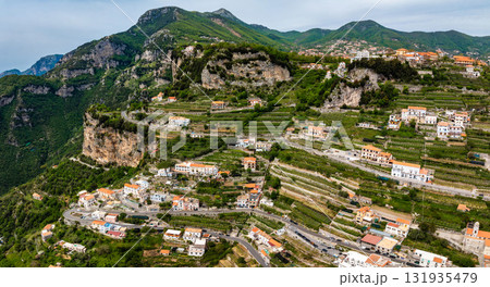 Aerial view of the Amalfi Coast in Italy, showing terraced hillsides, pastel colored buildings, winding roads, and lush greenery against rugged cliffs. Aerial view of the Amalfi Coast in Italy, showing terraced hillsides, pastel colored buildings, winding roads, and lush greenery against rugged cliffs. 131935479