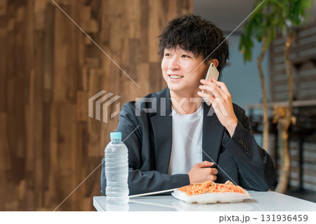 食堂・カフェでランチを食べながらスマホで電話するビジネスマン・男性 食堂・カフェでランチを食べながらスマホで電話するビジネスマン・男性 131936459