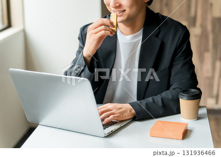 カフェで軽食を取りながらパソコンを使って仕事するビジネスマン・男性 カフェで軽食を取りながらパソコンを使って仕事するビジネスマン・男性 131936466